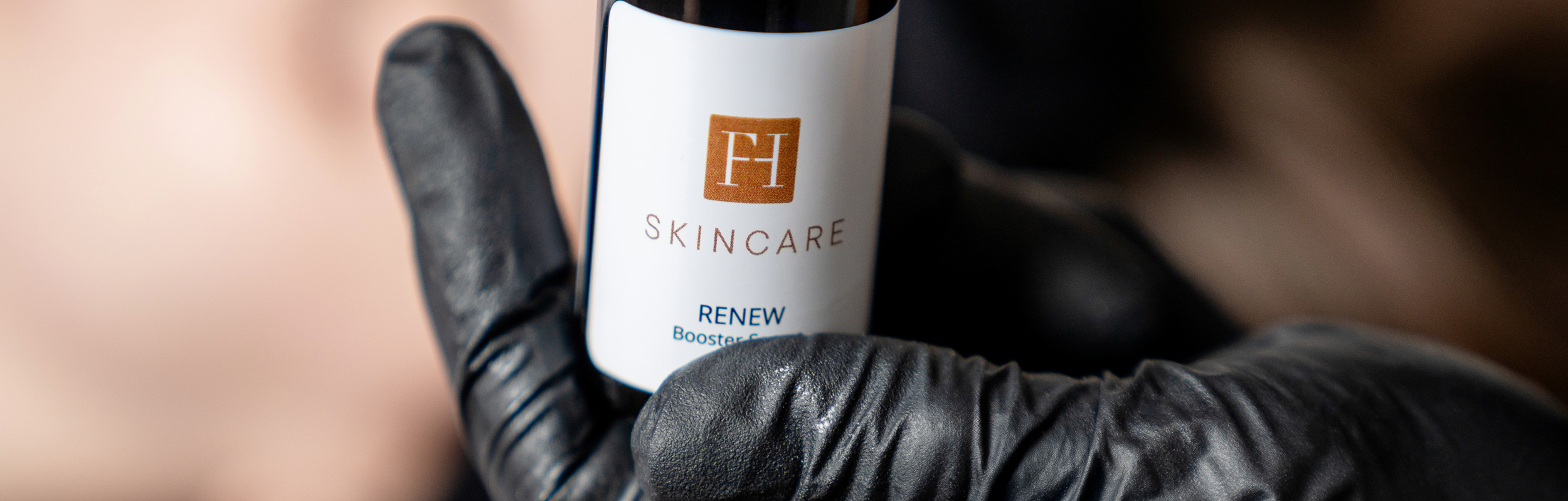Serumflasche „FH Skincare Renew“ wird mit Handschuh gehalten.
